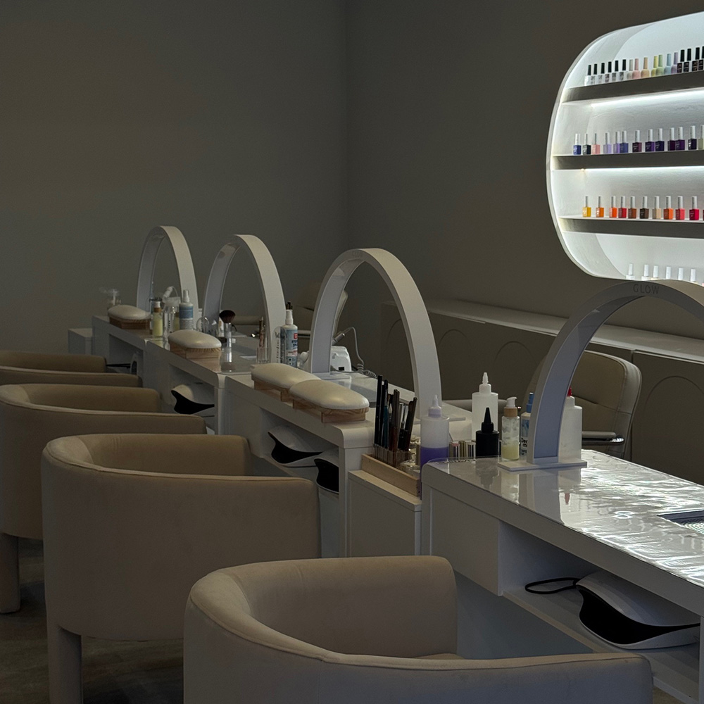 Ein eleganter Nagelsalon mit cremefarbenen Stühlen und schöner Beleuchtung.